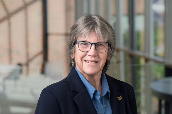 Eileen Ring's headshot with a blurred out background of windows and a brick wall.